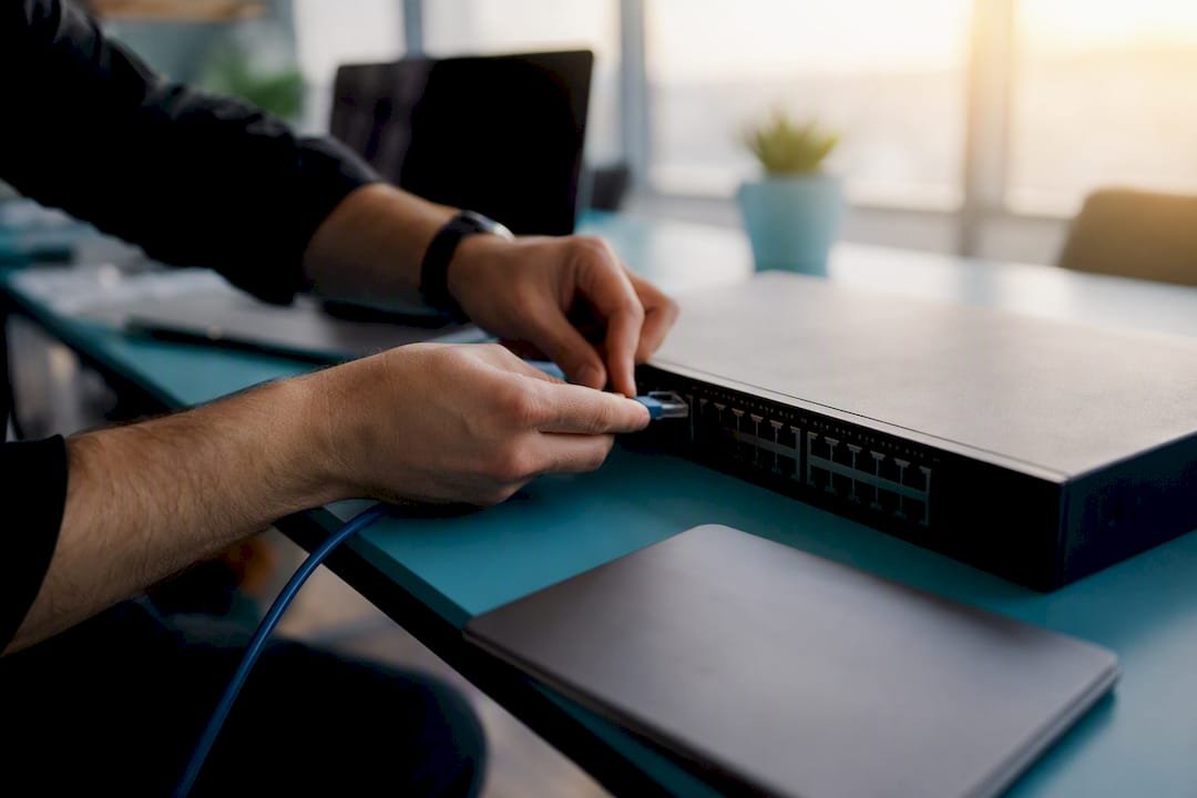 Finansinių technologijų biure darbuotojai jungia šviesolaidinį kabelį – čia viskas sukasi apie inovacijas ir patikimą ryšį.